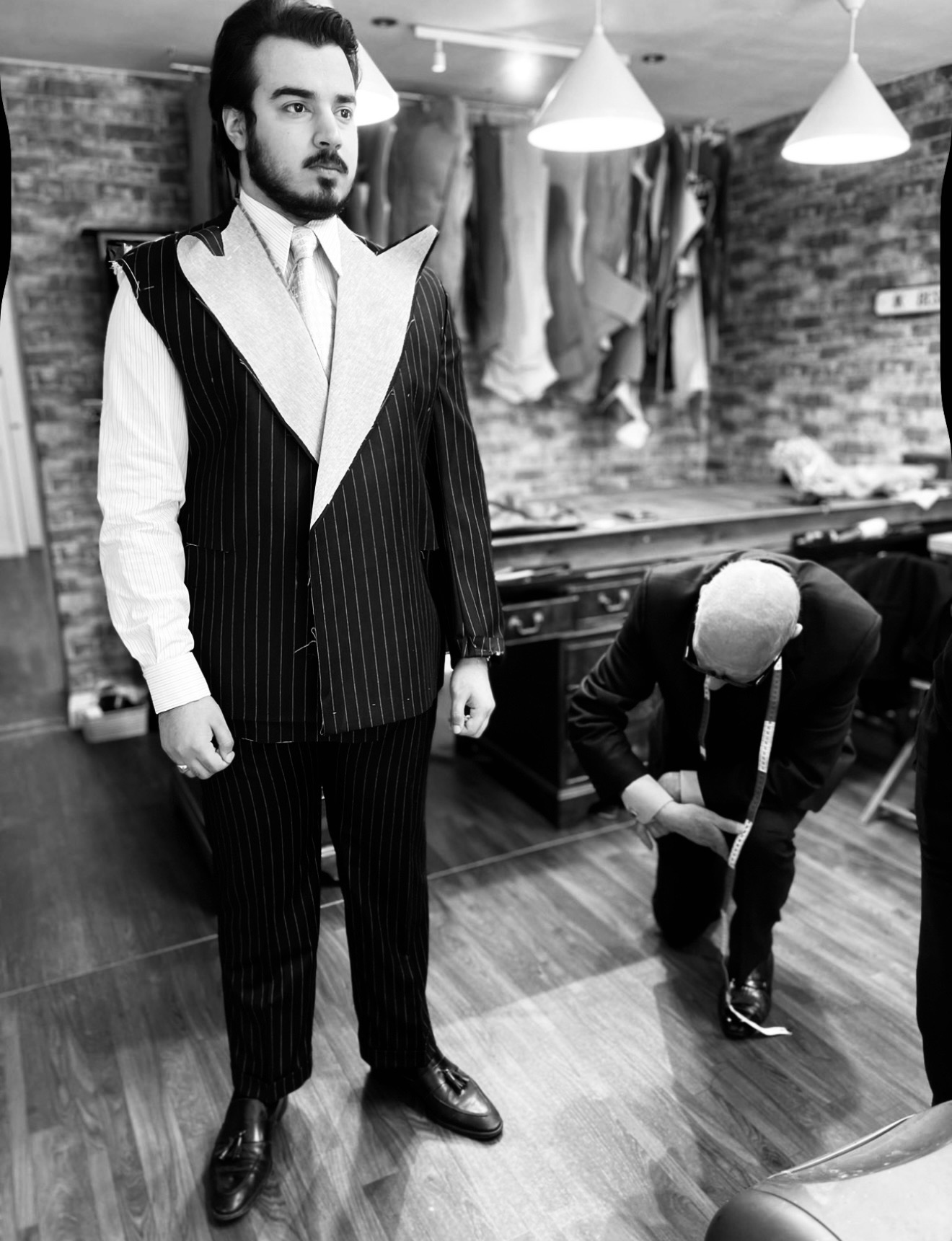 Groom standing for a pinstripe suit fitting in the IK Collection Bradford workroom